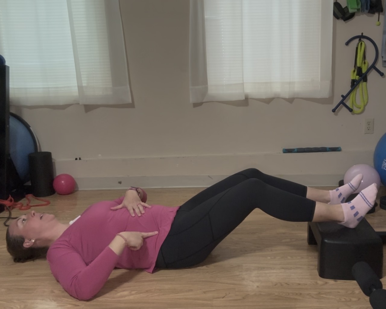 a women lying on her back preparing for a bridge and checking rib and pelvis position
